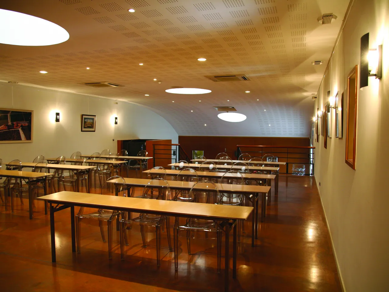 Salle de conférence moderne avec tables en bois, chaises transparentes, éclairage chaleureux et sol en bois foncé chez Millesima à Bordeaux