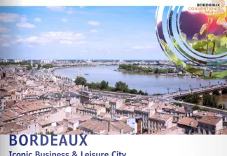 Vue aérienne de Bordeaux montrant le centre-ville avec ses toits en terre cuite, la Garonne, les ponts et les quartiers modernes en arrière-plan sous un ciel bleu. Logo du Convention Bureau de Bordeaux et slogan 'Iconic Business & Leisure City' visibles.