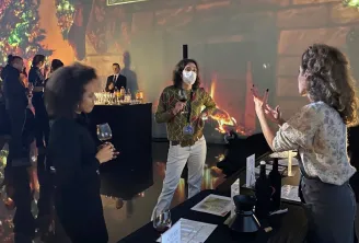 Dégustation de vins aux Ateliers de Bacchus à Bordeaux, avec des participants découvrant des vins à une table décorée pendant qu'un animateur anime la séance devant un grand écran lumineux.