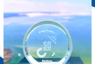 Trophée Green Trophy affichant le logo SO avec la marque Bordeaux, mettant en avant la reconnaissance environnementale remportée par Arcachon Ecotours, sur un fond de paysage côtier.