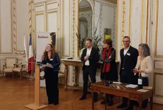 Cinq personnes debout dans une salle richement décorée de style 18ème siècle aux murs blancs et dorures, lors d'un événement officiel à l'occasion du 18ème anniversaire du Club des Ambassadeurs de Bordeaux.