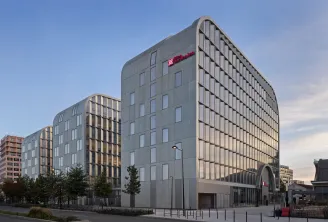Bâtiment moderne de l'hôtel Hilton Garden Inn à Bordeaux centre-ville, présentant une architecture contemporaine avec façade grise, panneaux nervurés verticaux, plusieurs étages aux fenêtres régulières, et entrée au rez-de-chaussée, dans un environnement 