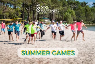 Groupe de participants courant sur une plage de sable lors des Summer Games XXL Happyness à Bordeaux, avec des arbres et de l'eau visibles en arrière-plan, et un filet de volley-ball installé sur la plage.