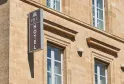 Façade du Best Western Premier Hôtel Bayonne Etche Ona à Bordeaux, bâtiment en pierre beige d'architecture classique, avec enseigne hôtelière sombre, fenêtres symétriques aux encadrements de pierre et corbels décoratifs.