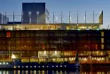 Bâtiment hôtel contemporain illuminé au crépuscule avec architecture vitrée et métallique, reflété dans l'eau du port de Bordeaux