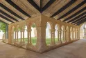 Cloître en pierre de style roman avec arcades et colonnes, recouvert d'une structure moderne en bois, aux Cordeliers à Bordeaux
